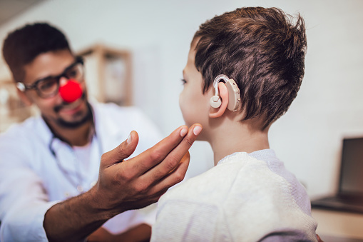 imagen de un profesional sanitario atendiendo a un niño que está utilizando un sonotone